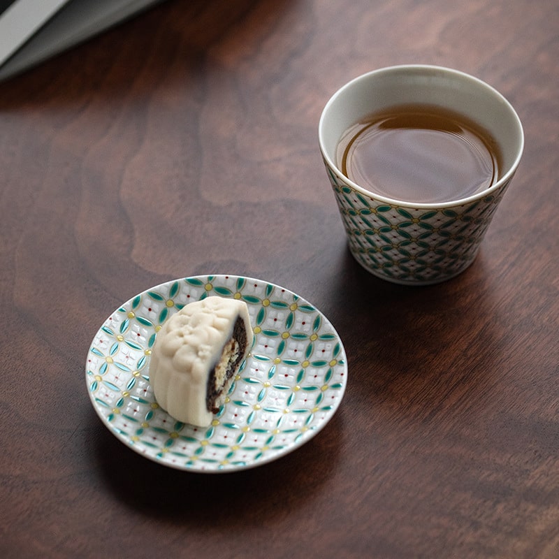 Bottom view of the patterned ceramic cup and saucer on a neutral background.