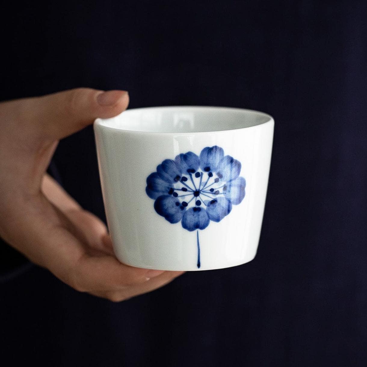 Japanese tea cup being filled with water, showcasing underglaze floral pattern.