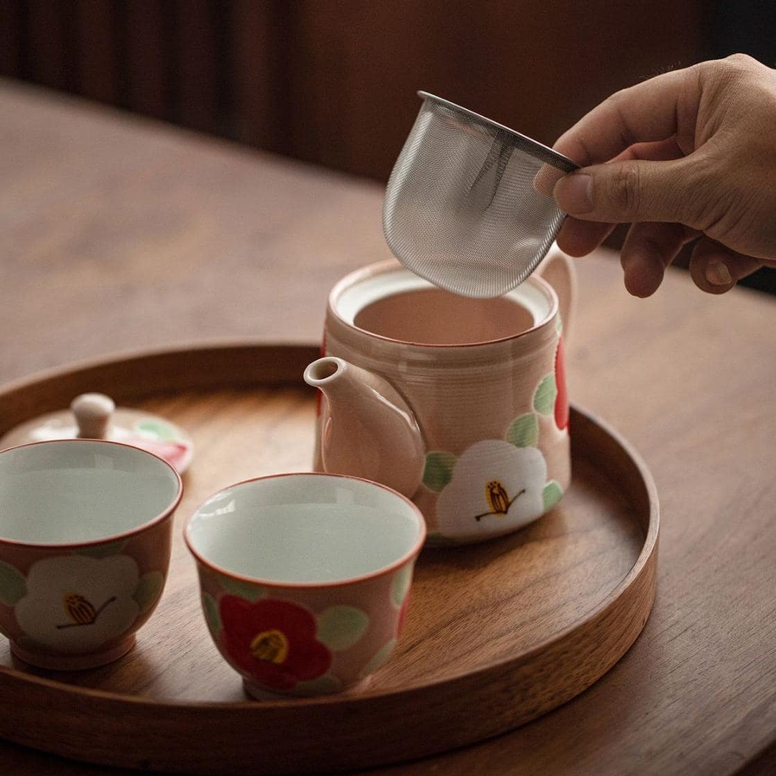 Elegant pink teapot and matching cups with floral design.