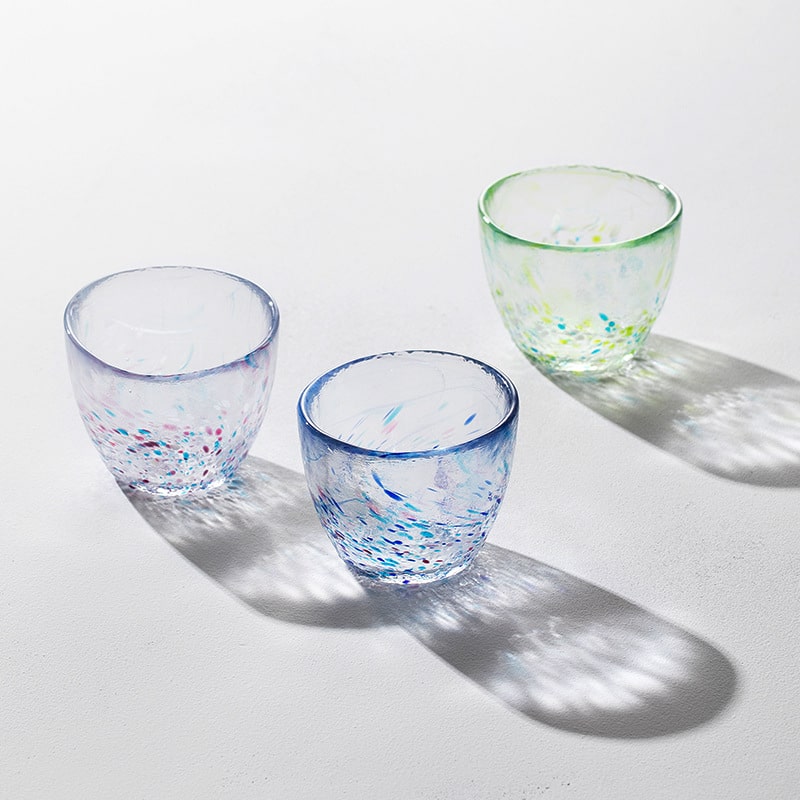 Hand-blown colorful artisan glass cup on white background.