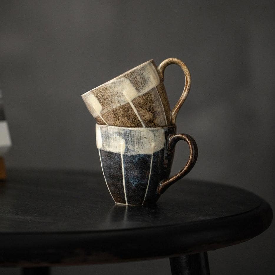 Green and striped ceramic mugs held in hands