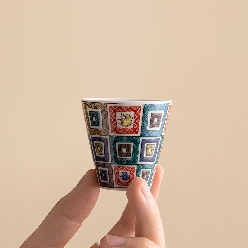 Hand holding a Japanese porcelain cup with intricate details