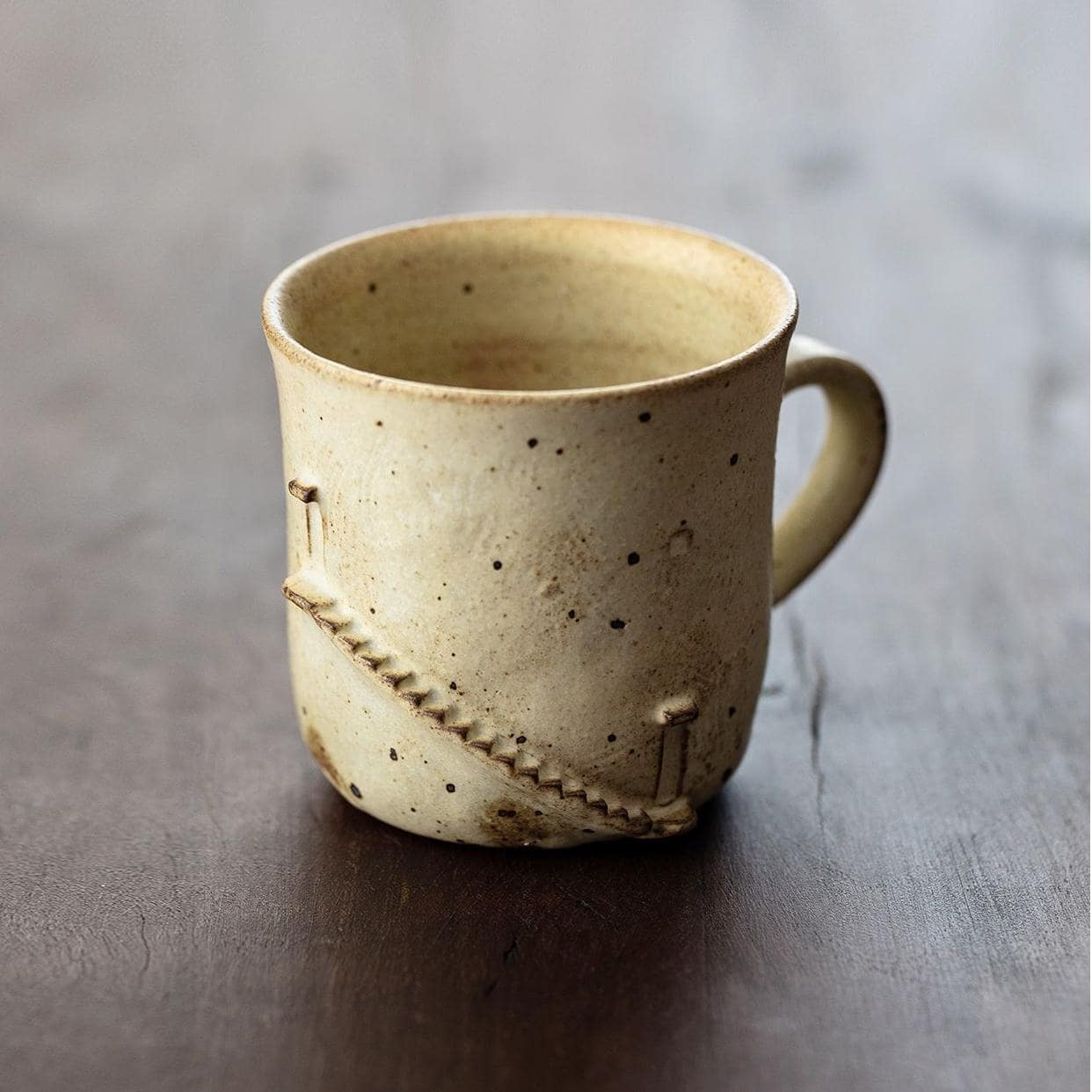 Rustic ceramic cup with speckled design and hand-carved details.