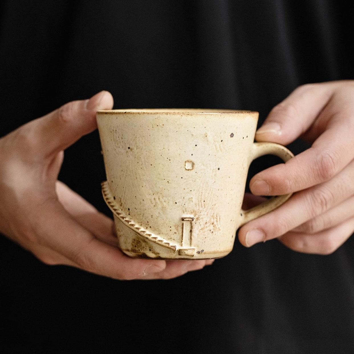 Speckled ceramic tea cup with ergonomic handle.