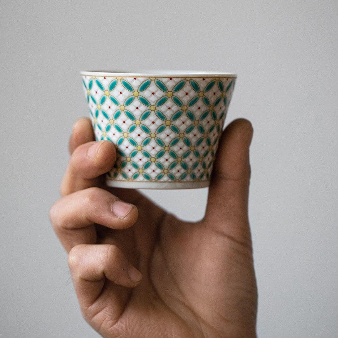 Ceramic cup and matching saucer set with teal and yellow patterns.