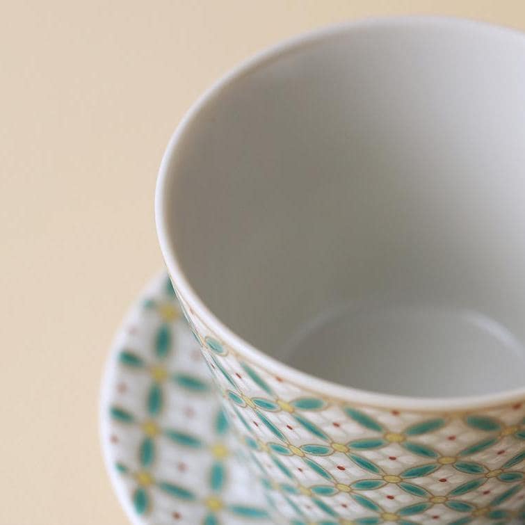 Modern ceramic cup with a colorful geometric pattern, displayed on a table.