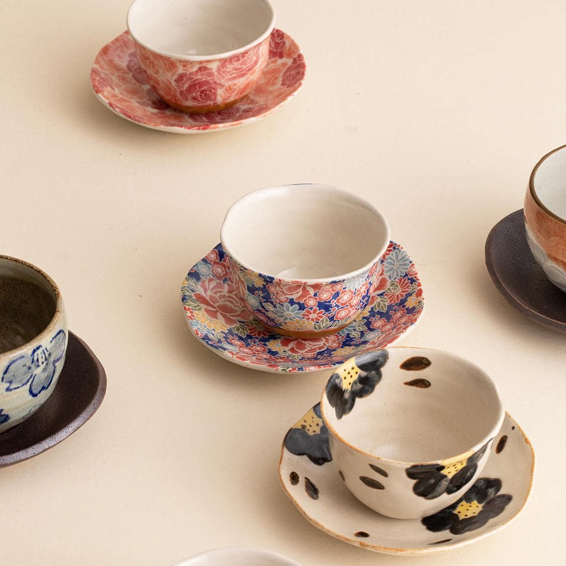 Collection of unique ceramic cup and saucer sets on wooden shelves