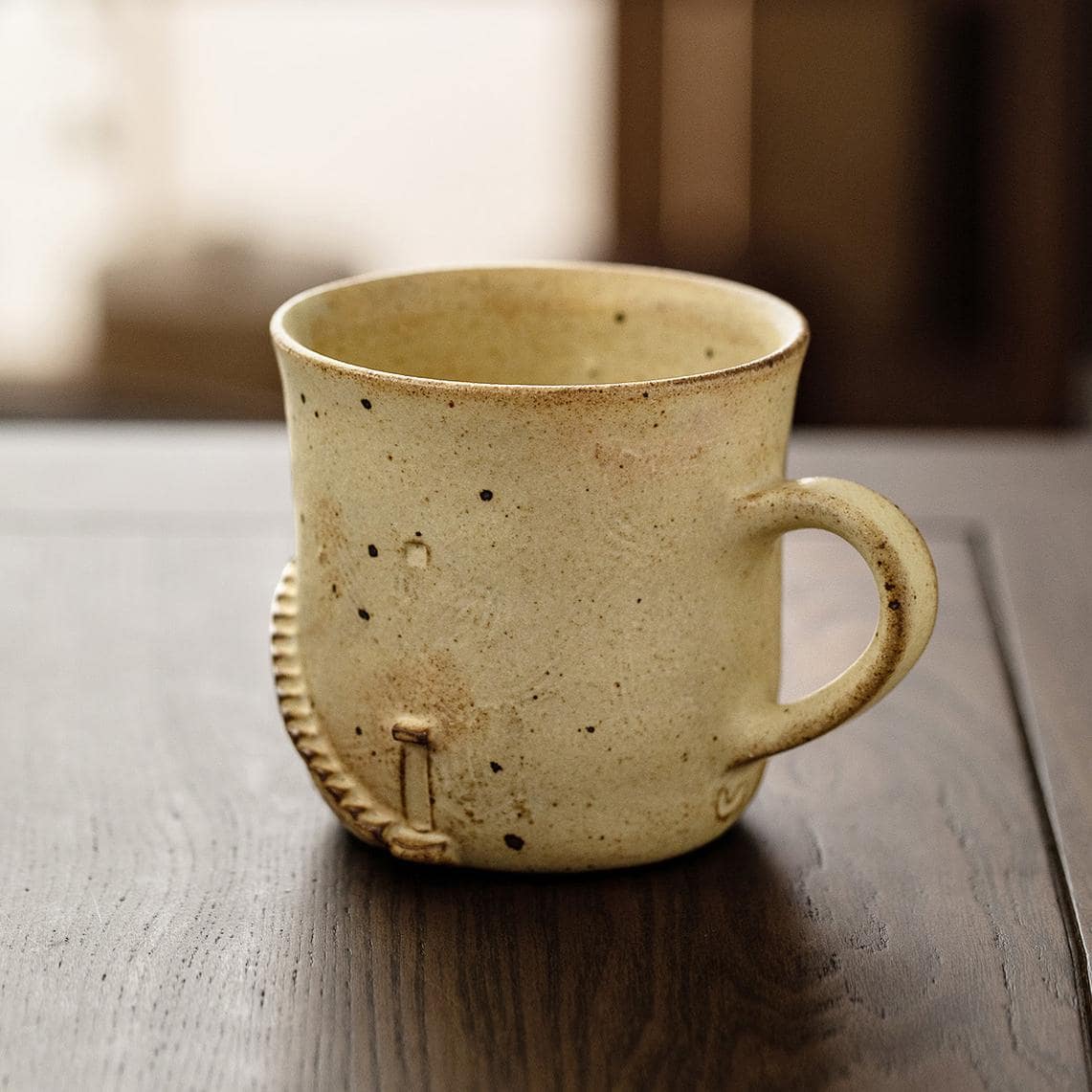 Rustic ceramic cup with speckled design and hand-carved details.