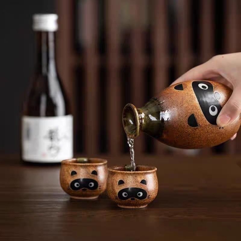 Hand-painted sake bottle and matching cups with raccoon designs.
