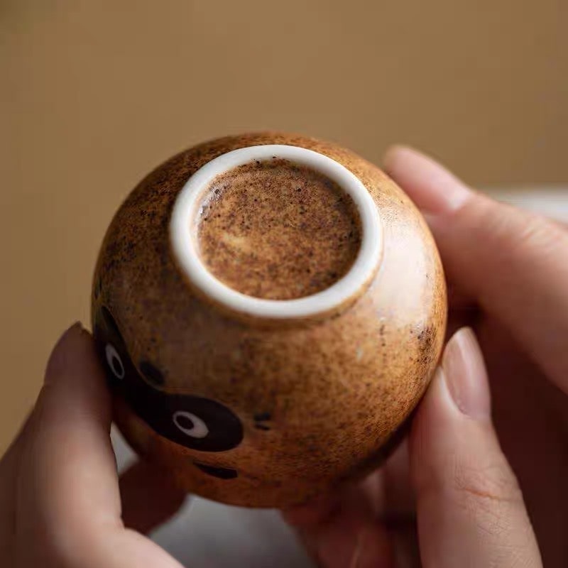 Close-up of raccoon-design ceramic sake cup and bottle.
