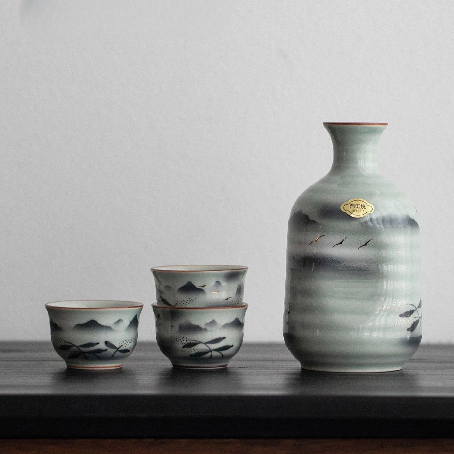 Ceramic sake set with hand-painted mountain and landscape designs.
