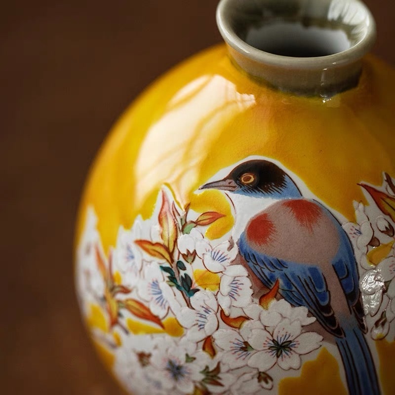 Close-up of ceramic sake cups with cherry blossom and bird details.
