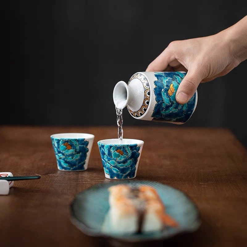 Hand-painted blue floral sake drinking set with a white ceramic base.
