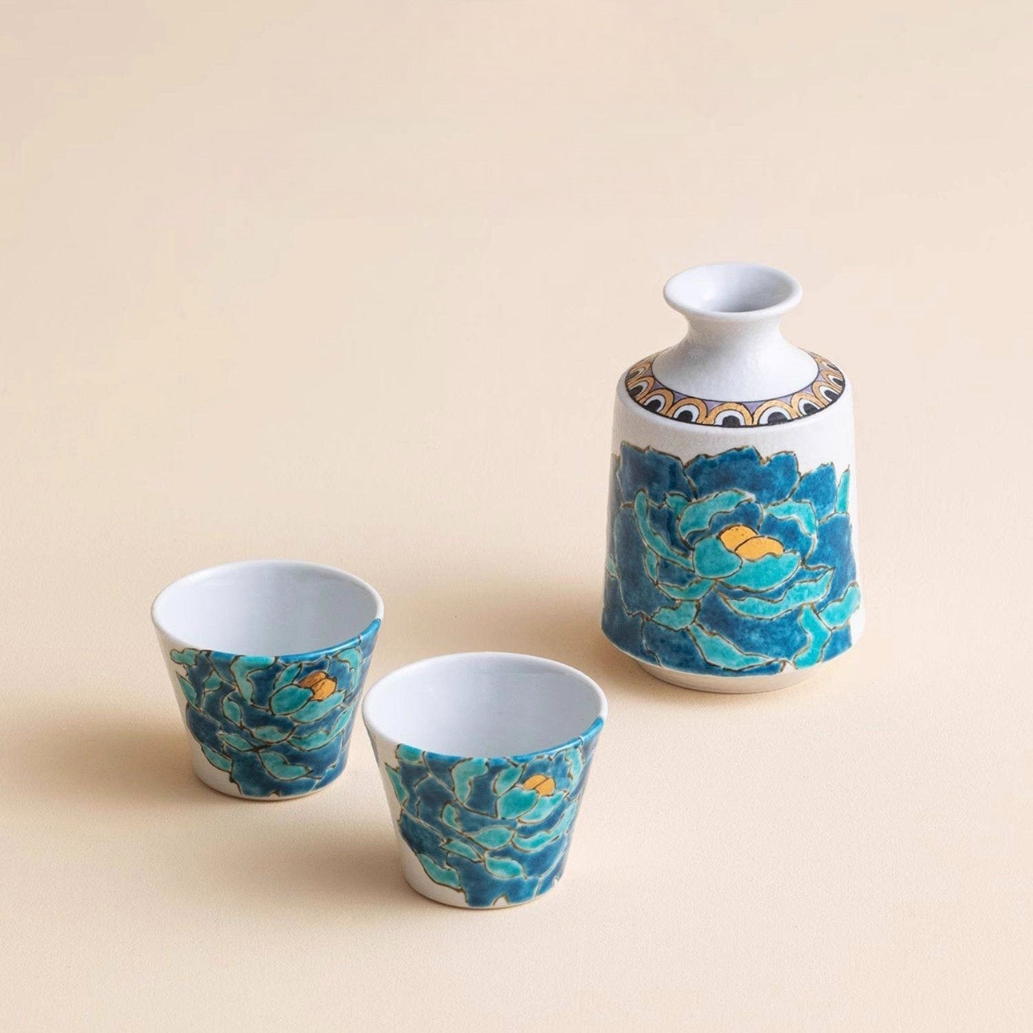 Ceramic sake set with vibrant blue peony and gold accents.
