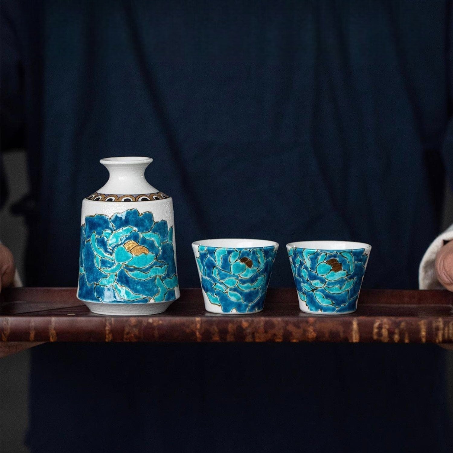 Hand-painted blue floral sake drinking set with a white ceramic base.
