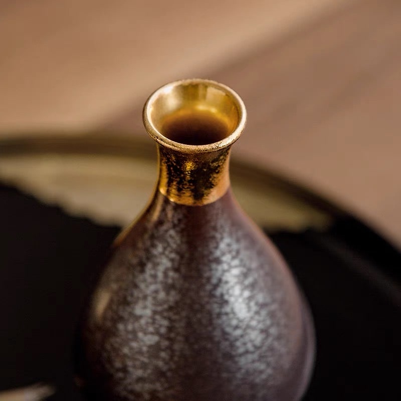 Shimmering gold and black ceramic sake set for formal occasions.
