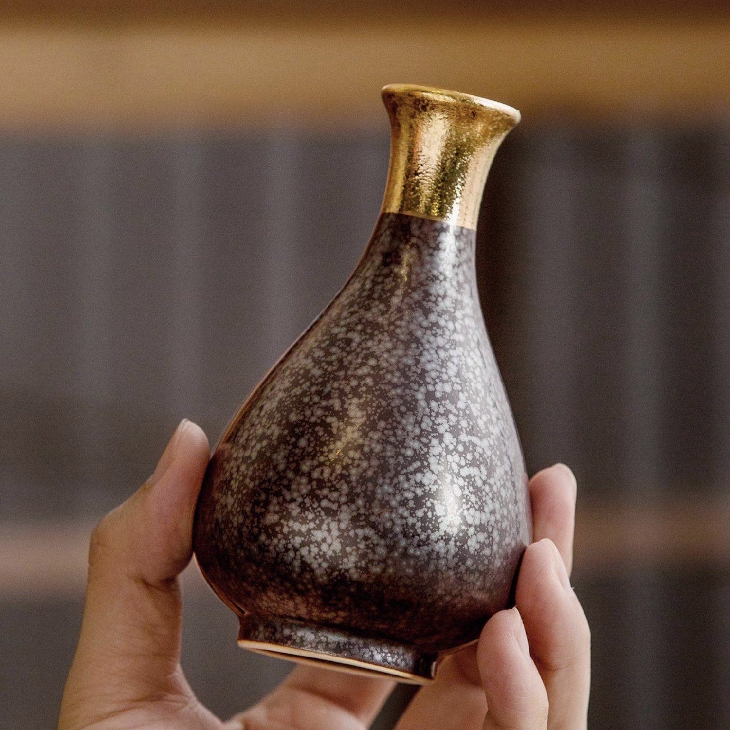 Shimmering gold and black ceramic sake set for formal occasions.
