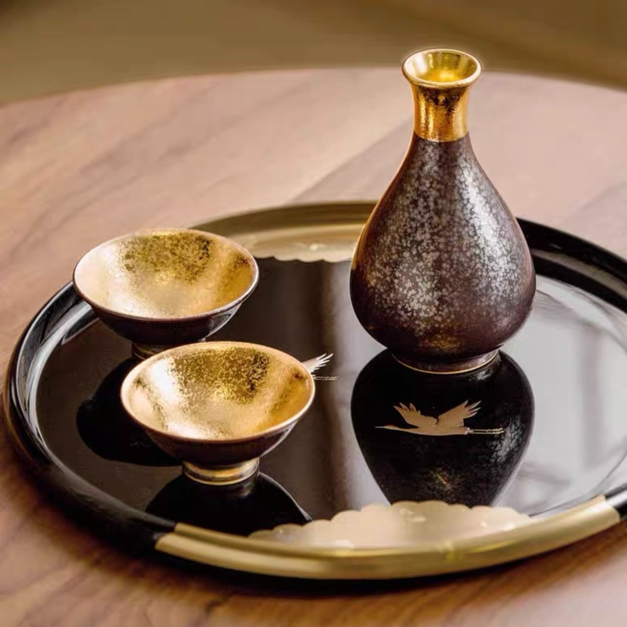 Luxurious sake set with a golden-lined cup and speckled black bottle.
