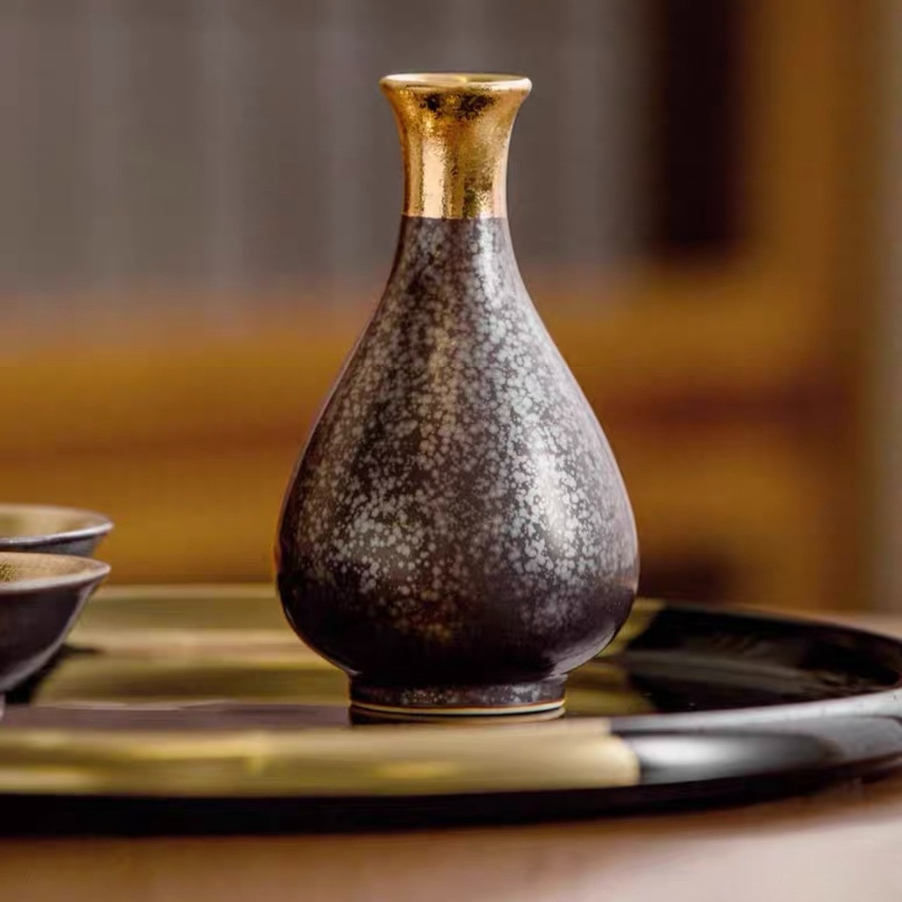 Close-up of golden interior cups paired with a sleek sake bottle.
