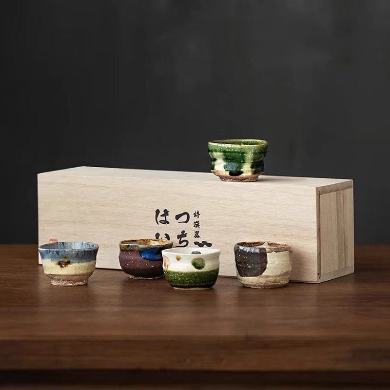 Handmade ceramic sake cups with rustic textures and earthy tones.
