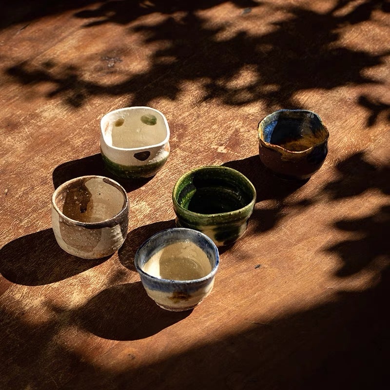 Handmade ceramic sake cups with organic shapes and earthy tones.
