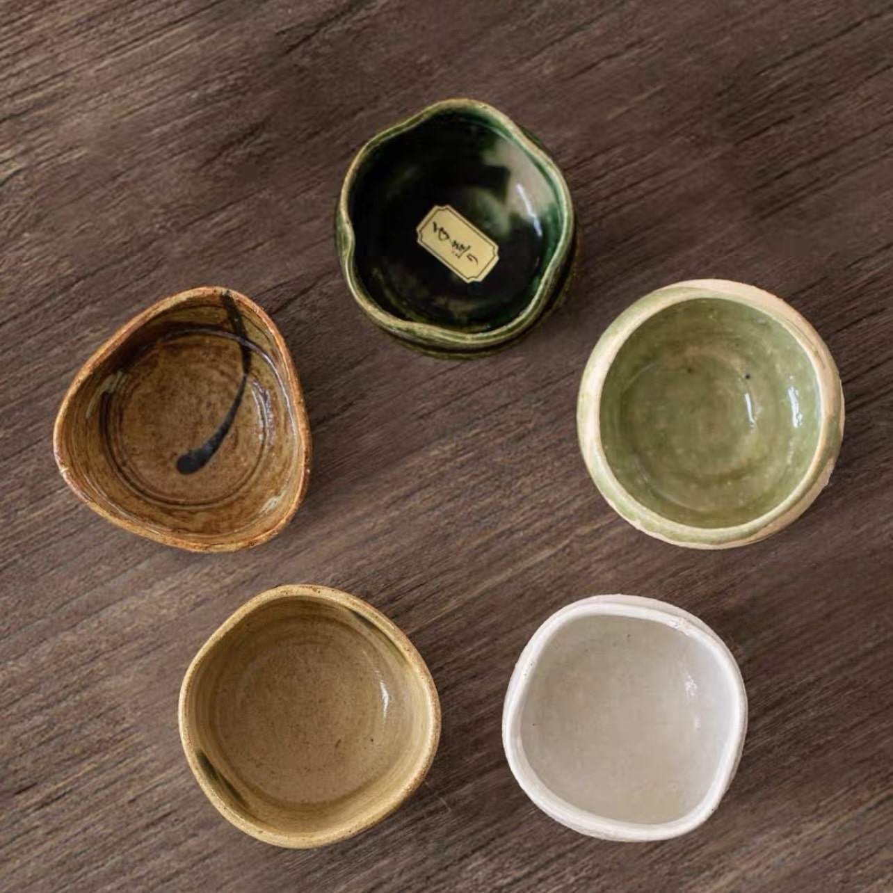 Close-up of individually shaped ceramic sake cups with unique designs.
