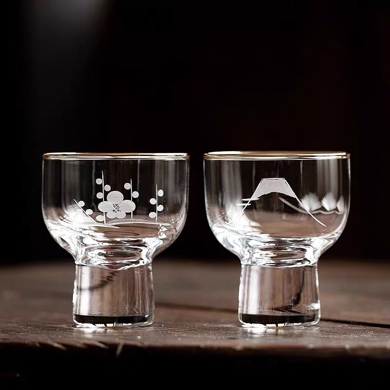 Glass sake cups with Mt. Fuji and cherry blossom engravings.
