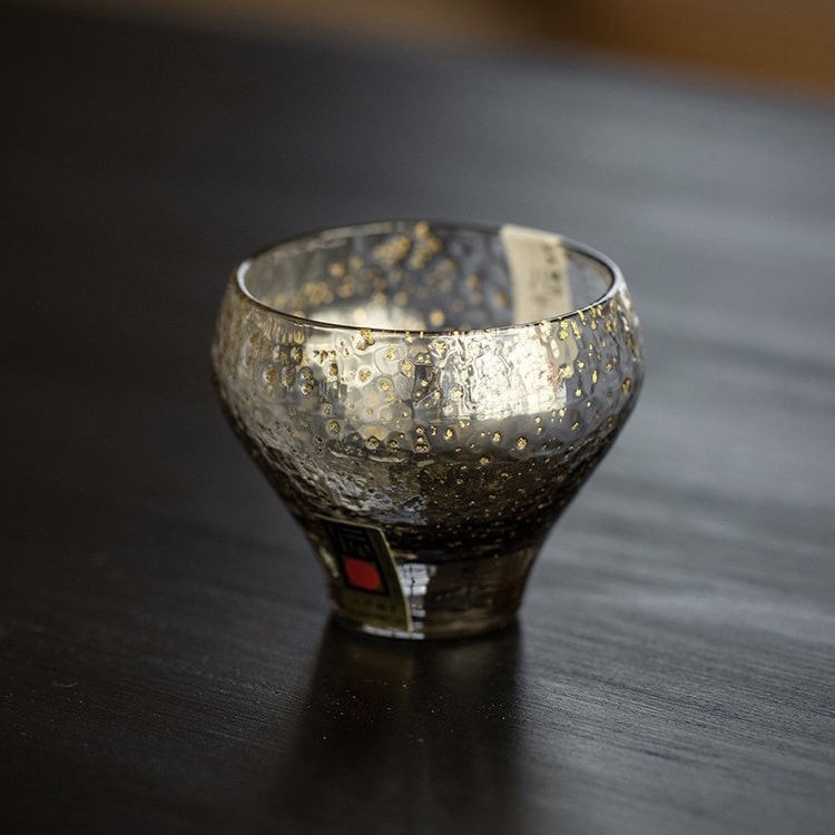 Elegant glass sake cups reflecting light on a white surface.
