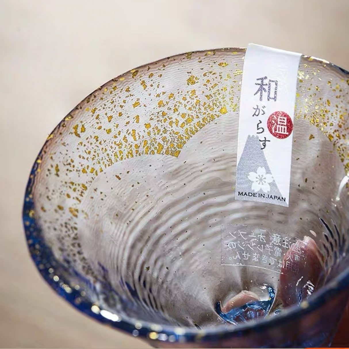 Elegant multicolor sake cup set with gold accents on a wooden table.
