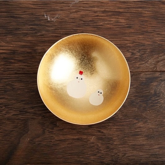 Artistic gold and red sake cup set displayed on a wooden table.
