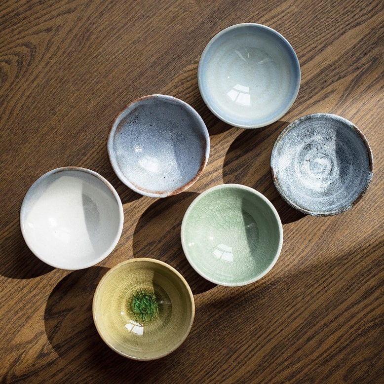 Artisan sake cup set displayed in a traditional wooden box.
