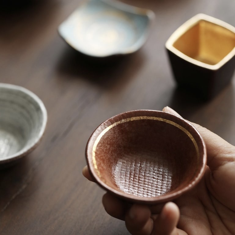 Close-up of Japanese sake cups featuring distinct artisan designs.
