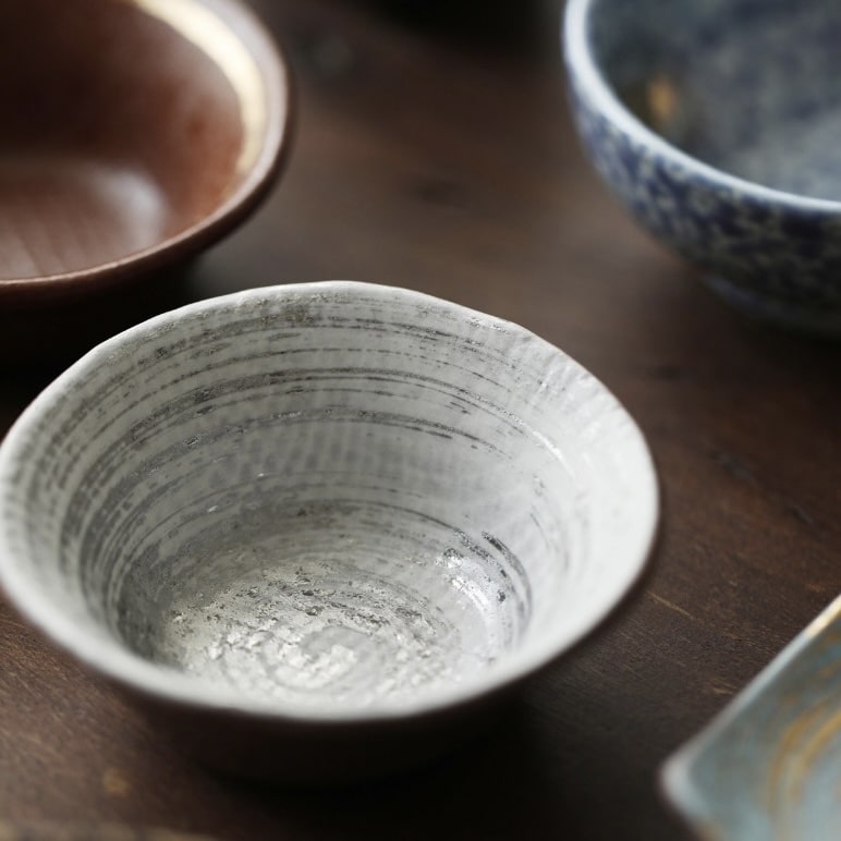 Close-up of Japanese sake cups featuring distinct artisan designs.
