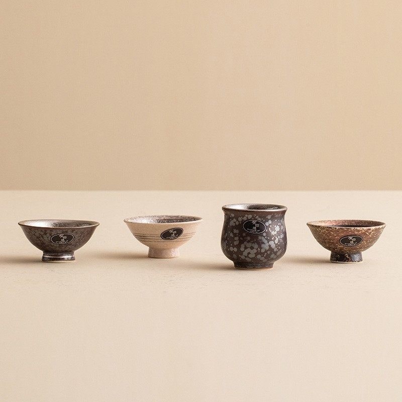 Set of four handcrafted ceramic tea cups with unique textures and designs.
