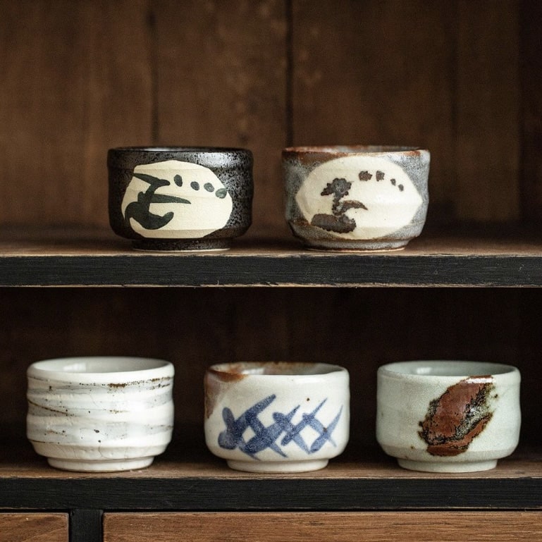 Set of handcrafted ceramic tea cups with textured finishes and earthy tones.
