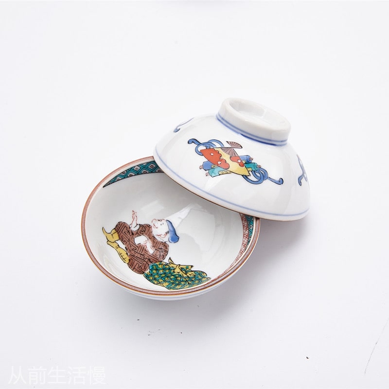 Japanese tea cup collection with folklore characters and decorative borders.
