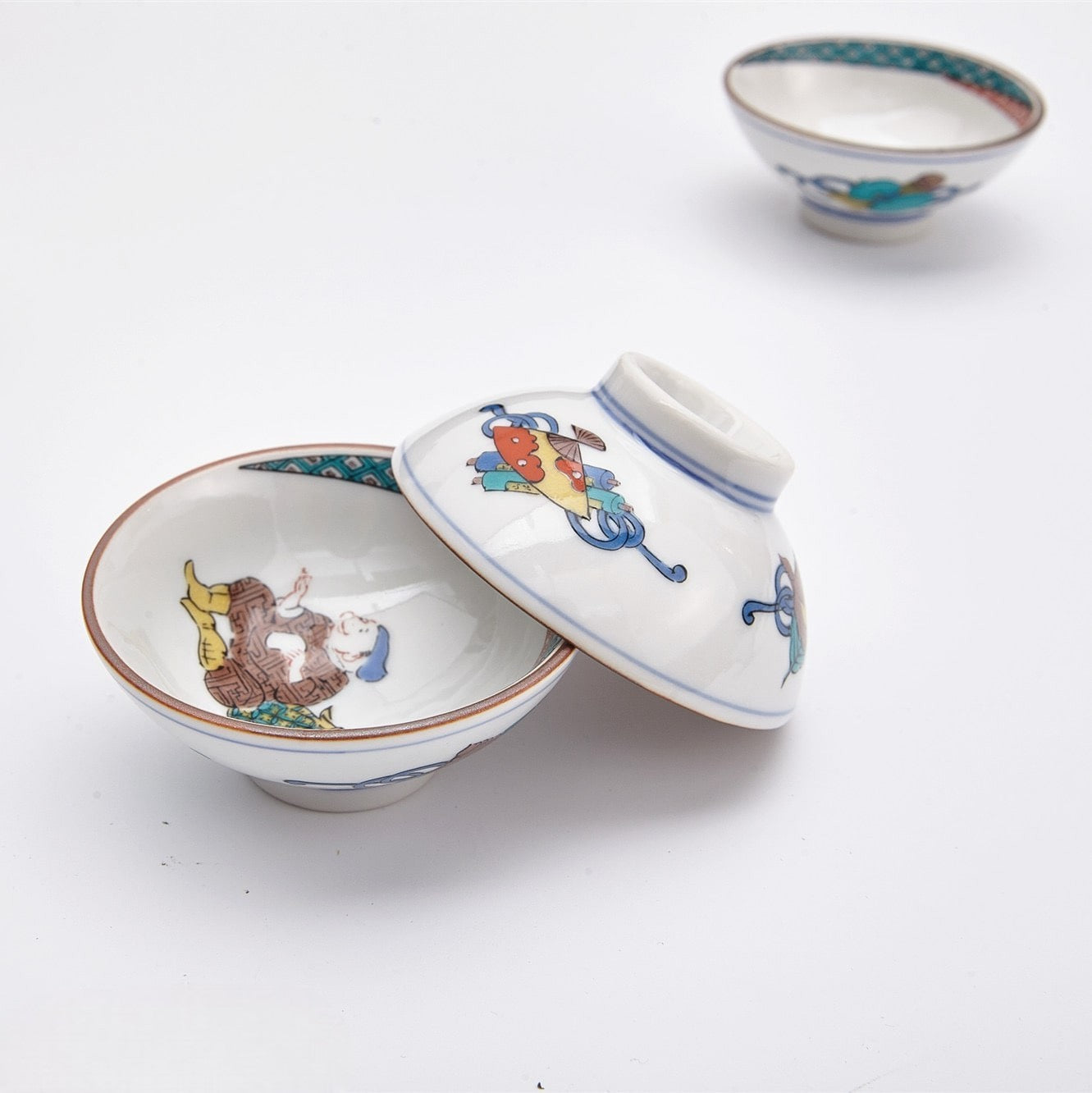 Close-up of traditional hand-painted sake cups with intricate designs.
