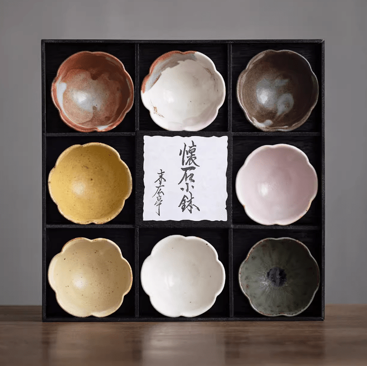 Handcrafted ceramic tea set with flower-shaped bowls in a black gift box.
