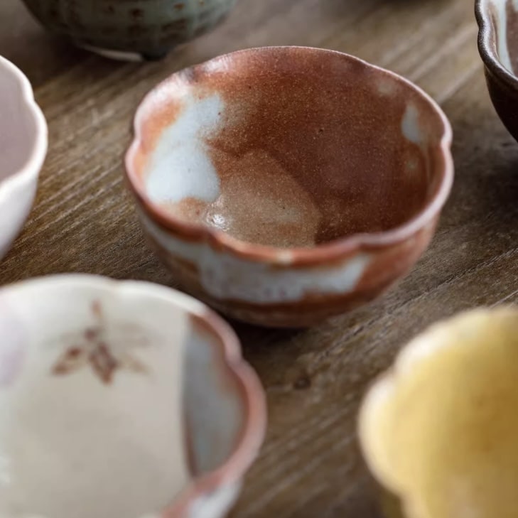 Elegant black box containing flower-inspired ceramic tea bowls.
