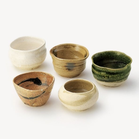 Set of five rustic ceramic tea cups with earthy tones.
