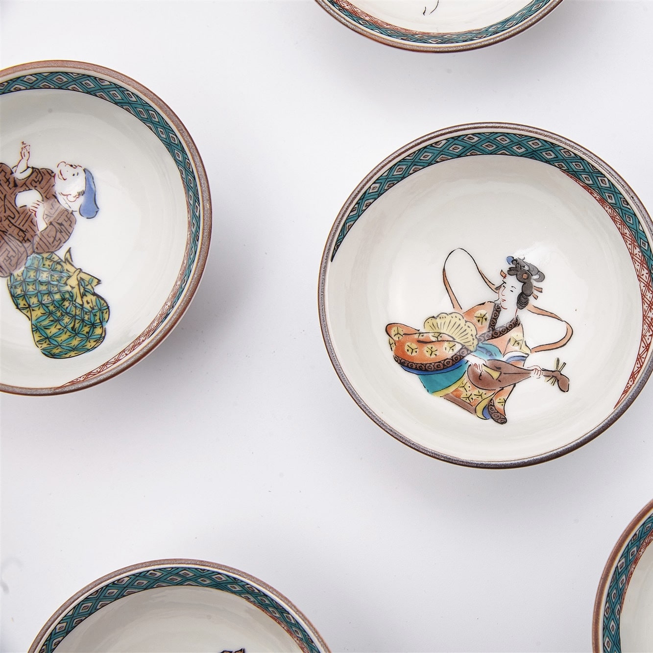 Close-up of vibrant hand-painted designs on Japanese porcelain tea cups.
