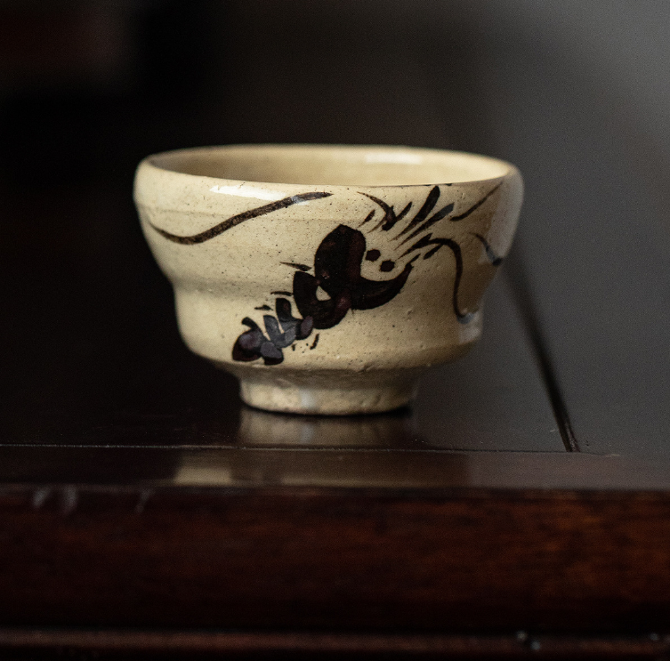 Handcrafted Japanese teacups with traditional patterns on a wooden shelf.