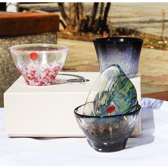 Artistic glass sake cups with vibrant details on a wooden table.