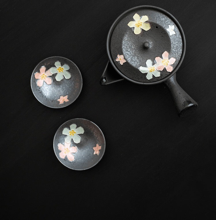 Elegant teapot and cups adorned with pastel cherry blossoms.