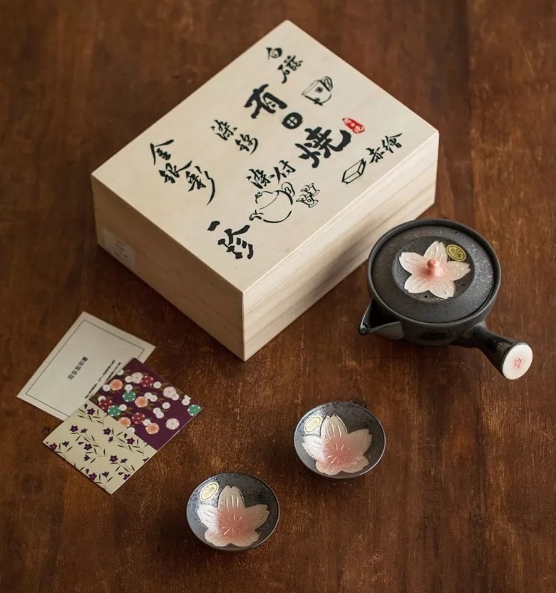 Wooden gift box with Japanese calligraphy and ceramic tea set featuring sakura flower designs.