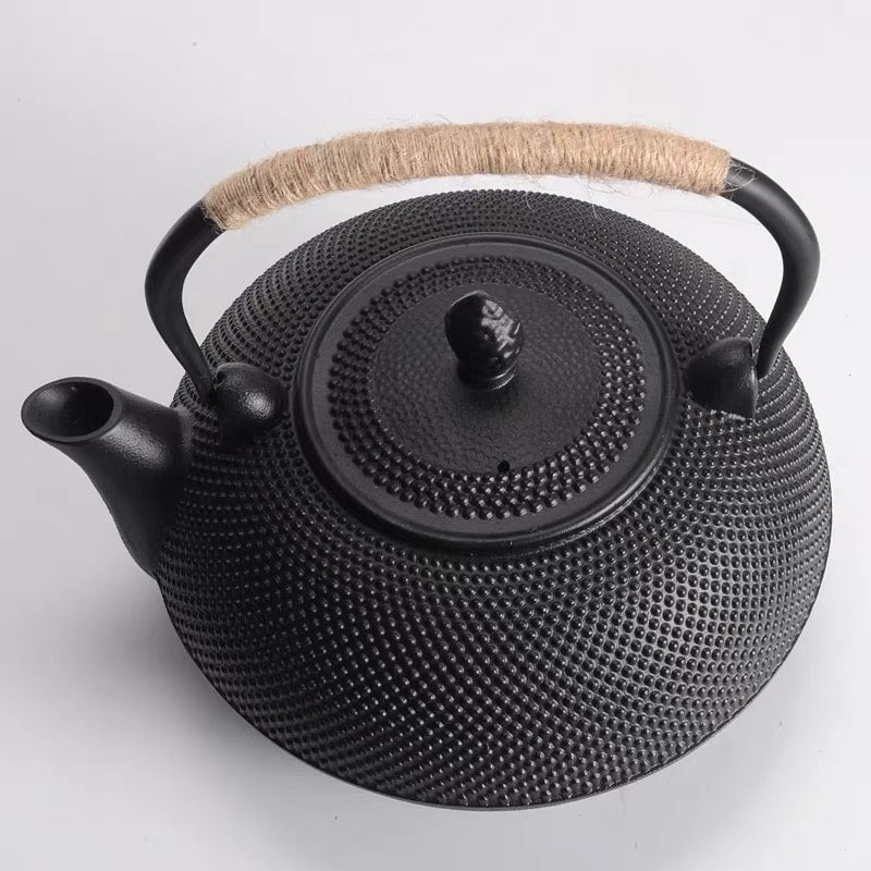 Elegant cast iron tea pot with a woven handle for heat retention.