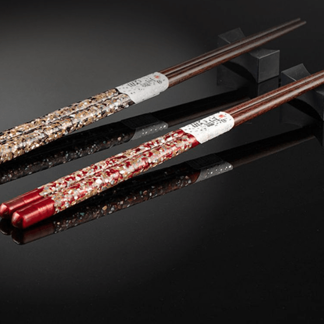 Close-up of handcrafted red and gold chopsticks with inlay details