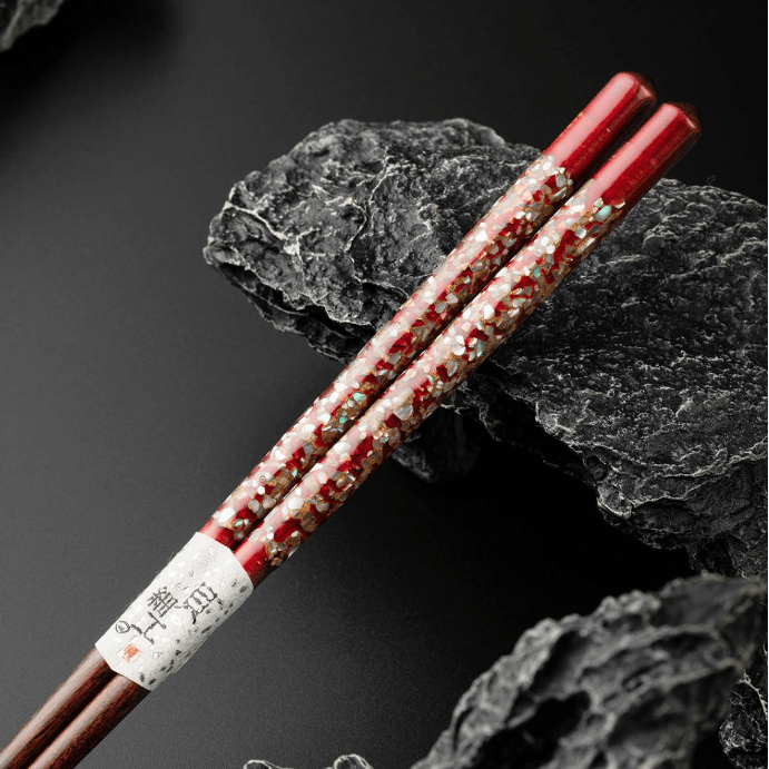 Artistic red chopsticks with shimmering inlays on a black background