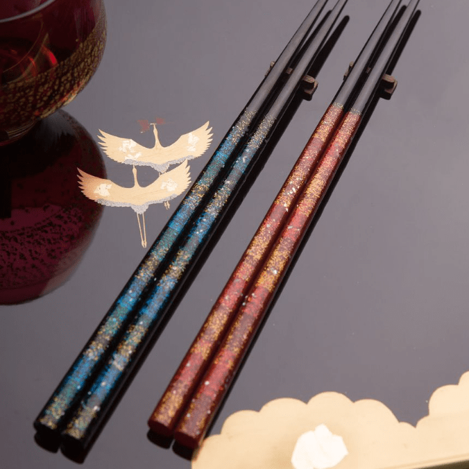 Red and blue glittering Japanese chopsticks on black plate