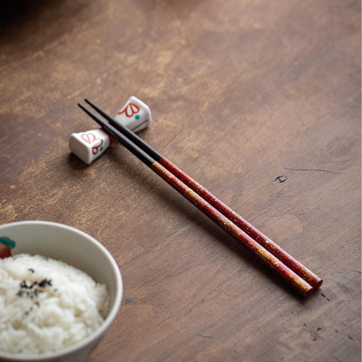 Red and blue glittering Japanese chopsticks on black plate